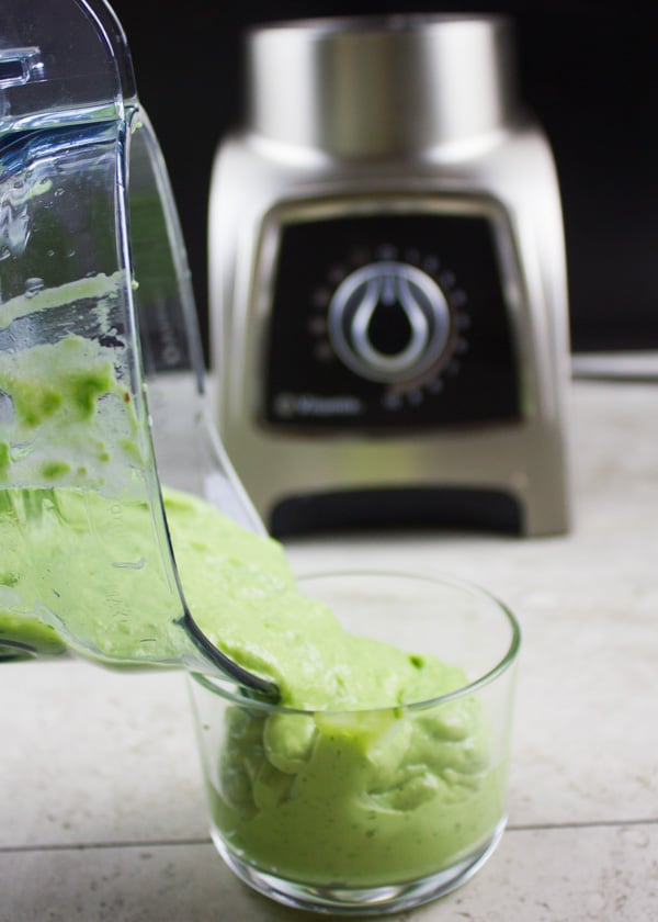 Avocado Crema in a mixer being poured into a glass dish 