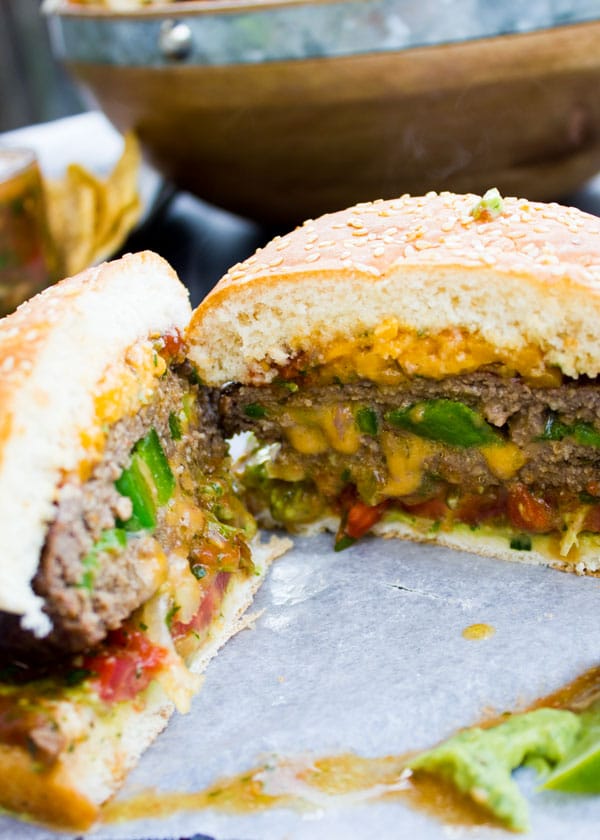 best lamb burger cut in half with visible layers of melted cheese, jalapeno slices and guacamole.