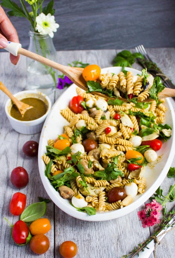 two wooden salad spoons serving a portion of Warm Antipasto Platter Pasta