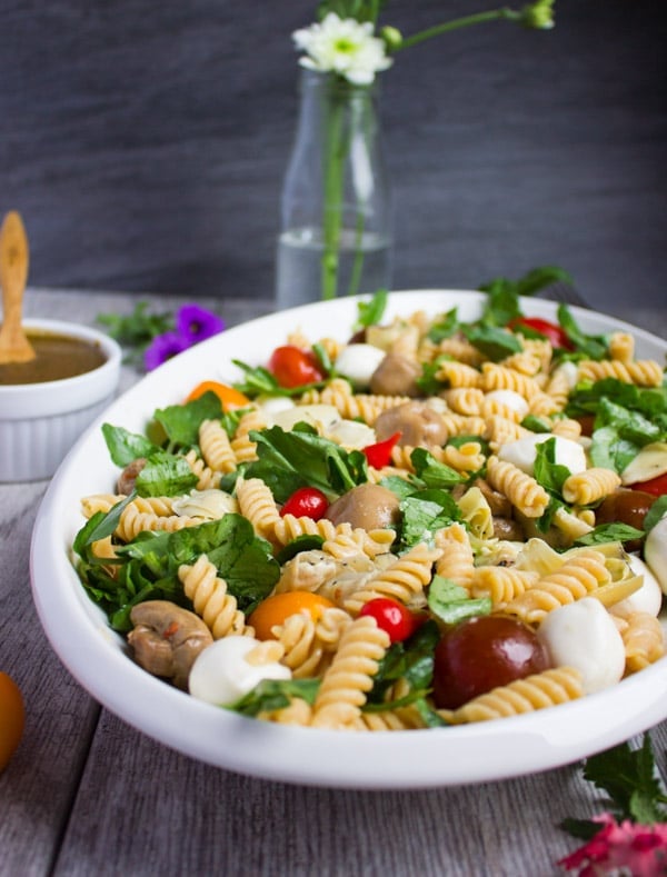 side view of a platter of Warm Antipasto Pasta with mozzarella and balsamic basil sauce