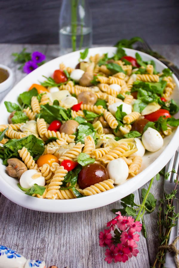 side view of Warm Antipasto Platter Pasta with basil sauce and mozzarella on a rustic table