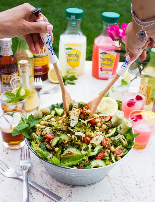 Mediterranean Farro Salad being tossed with wooden salad spoons.