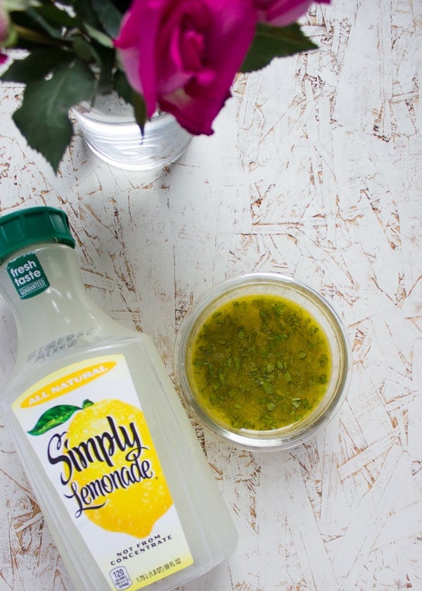  Sweet Zesty Lemonade Dressing in a small glass bowl next to a bottle of lemonade.