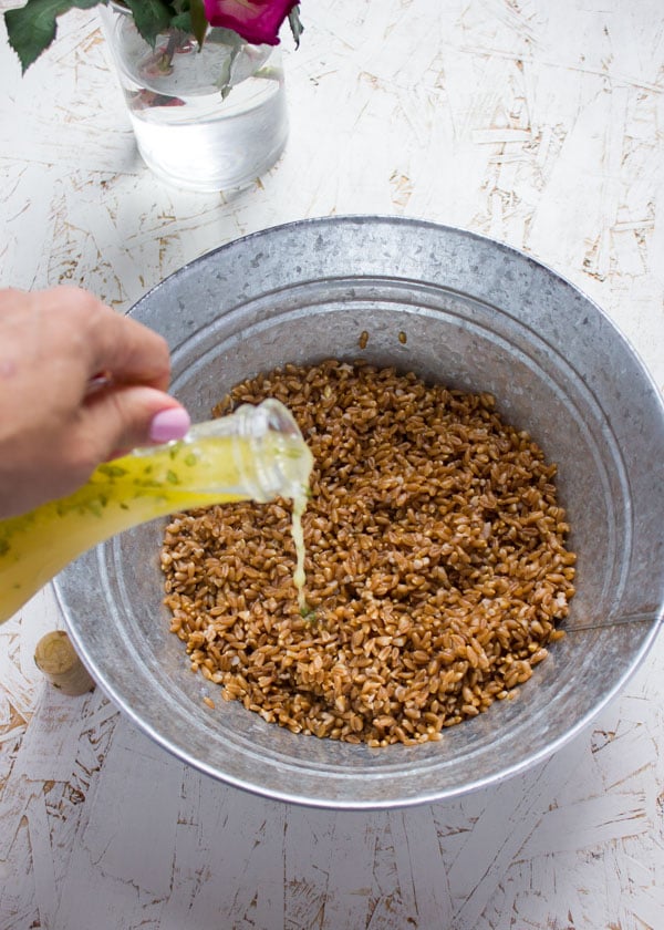 Sweet Zesty Lemonade Dressing being poured on top of a bowl with farro.