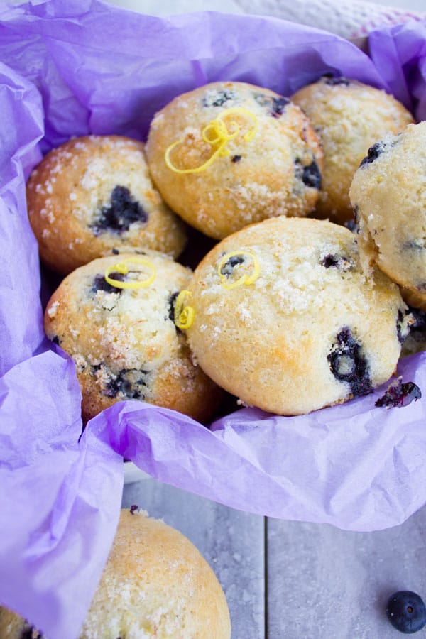 Blueberry Muffins With Lemon Sugar Crunch and lemon zest arranged in a box with purple paper lining