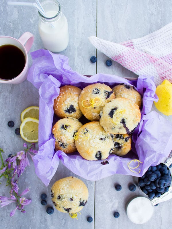 a box of Blueberry Muffins sprinkled with Lemon Sugar with a cup of coffee and a jar of milk