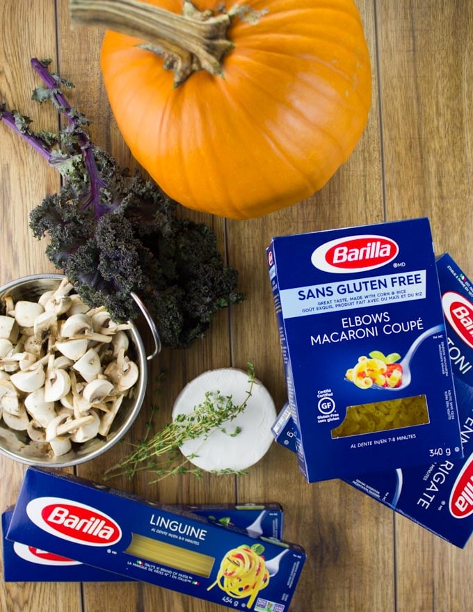 barilla pasta arranged on a table with kale and a pumpkin