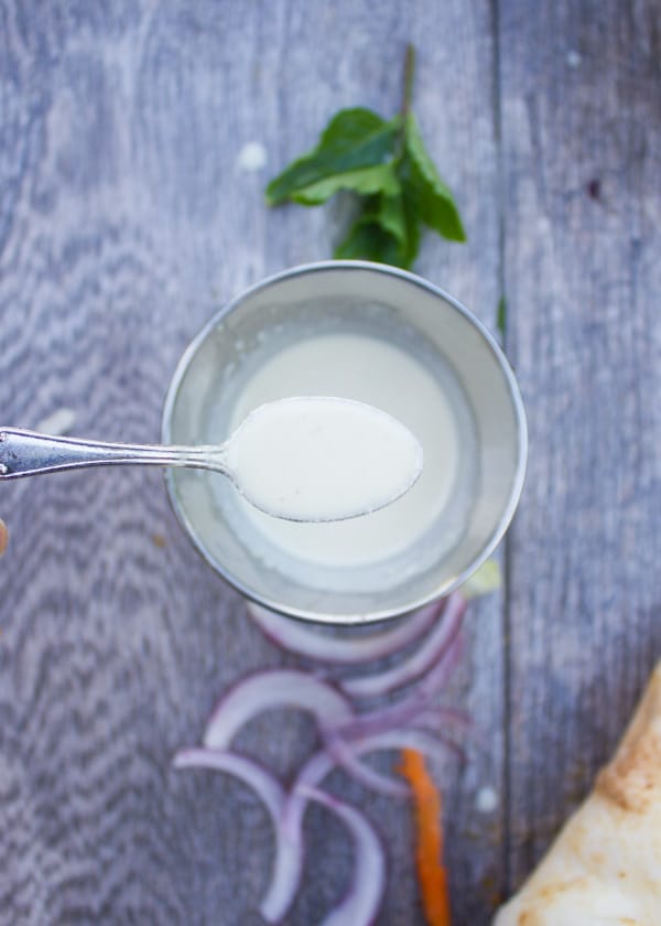 a glass bowl with tahini sauce on a rustic table