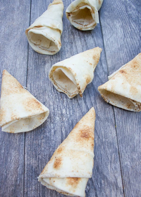 hand-rolled pita cones on a rustic wooden table ready to be filled.