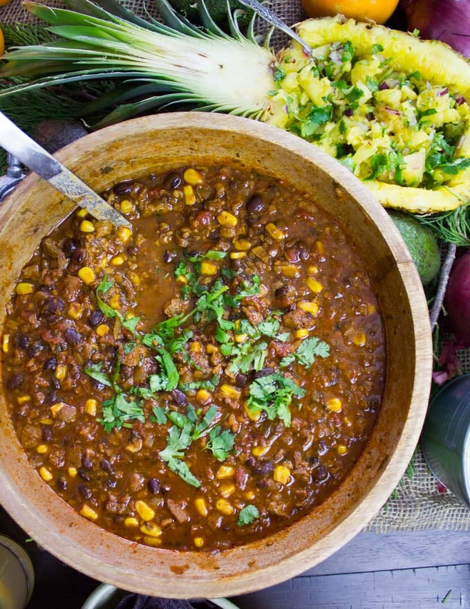 overhead shot of a bowl of Vegetarian Chili with a filled pineapple on the side