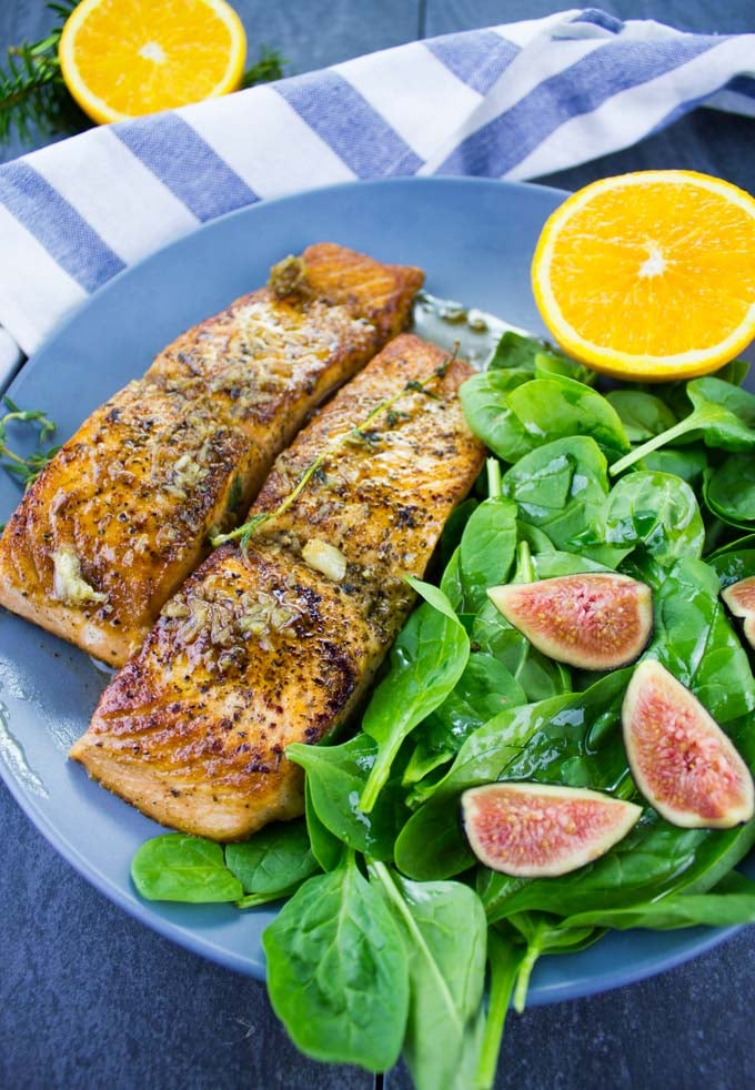 two Garlic Orange Pan-Seared Salmon fillets with a side salad