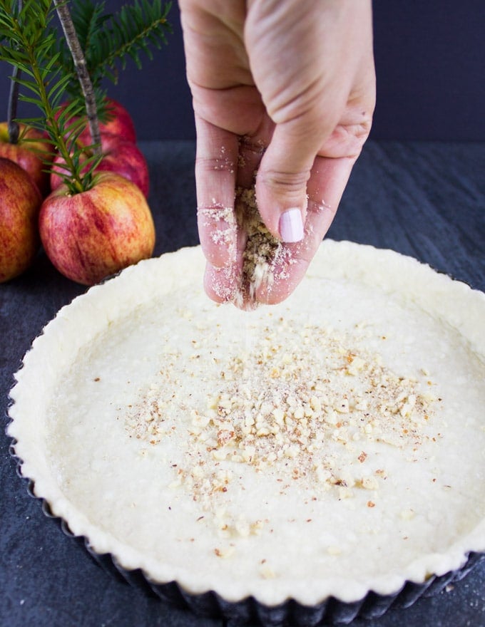 A tart shell being sprinkled with almonds for making Swiss Apple Tart