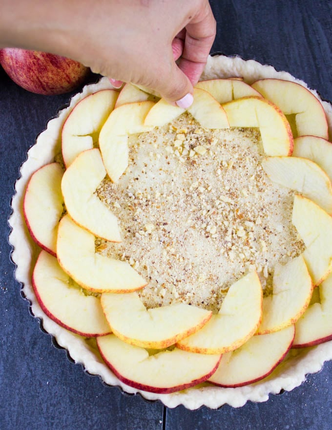 apple slices being arranged on top of a layer of almonds to make Swiss Apple Tart