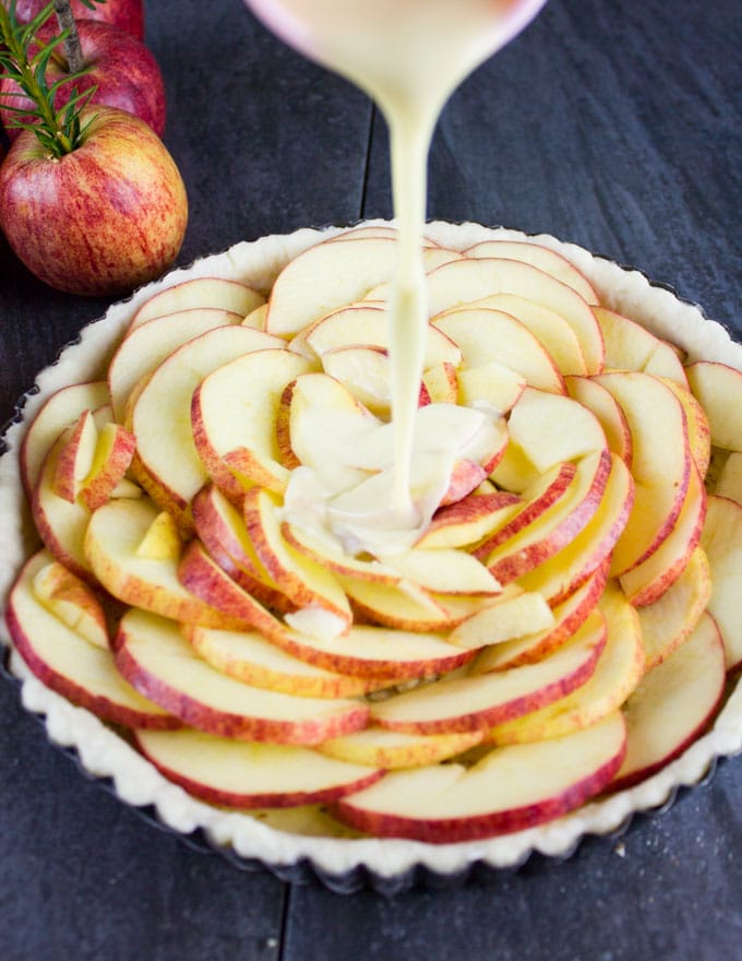 Vanilla Custard being poured on top of apple tart before baking