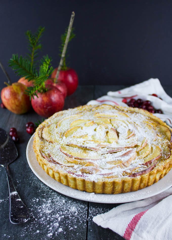 Swiss Apple Tart on a rustic wooden table with apples and spruce twigs in the background