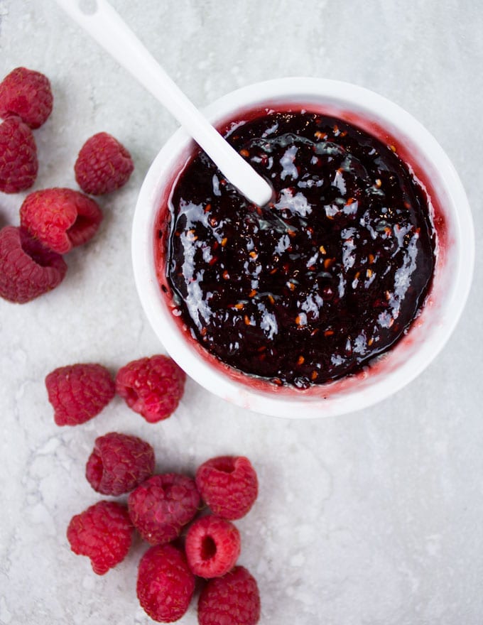 Raspberry Sauce is a small white dish with some fresh raspberries on the side