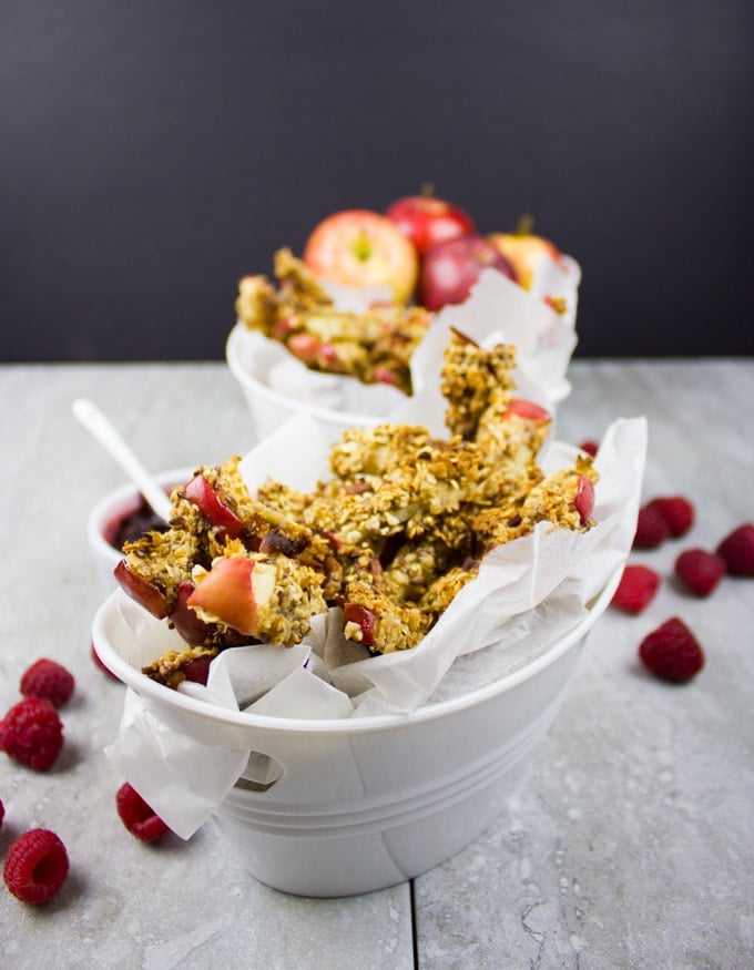 side view of 2 dishes with baked apple fries with fresh raspberries and a small bowl with raspberry sauce in the background