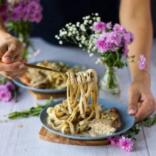 a hand stretching out some pasta to show the walnut sauce over the paste so delicious