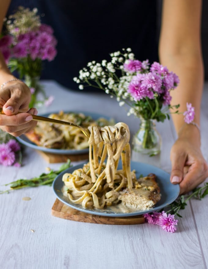 a hand stretching out some pasta to show the walnut sauce over the paste so delicious