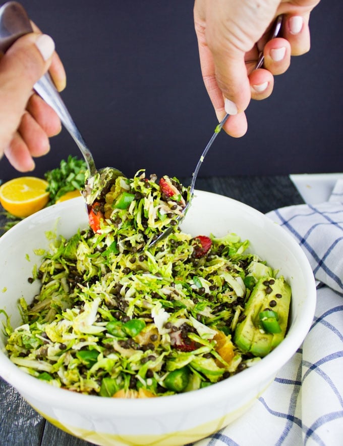 Citrus Lentil Salad with Shredded Brussel Sprouts being tossed in a salad bowl