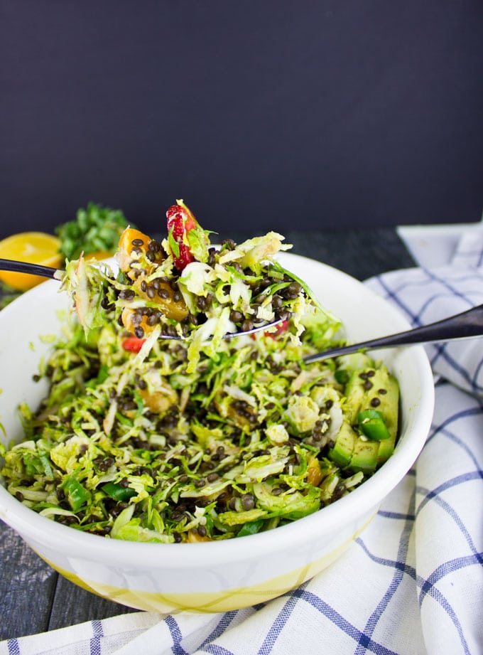 Citrus Lentil Salad with Shredded Brussel Sprouts being tossed in a salad bowl