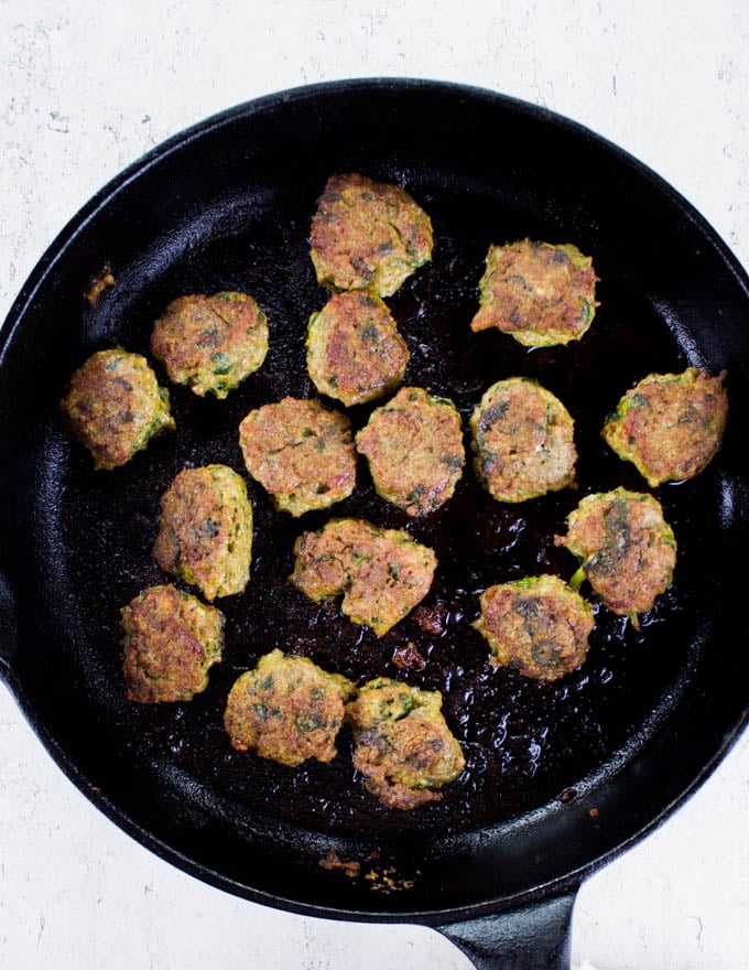 Thai Chicken Meatballs frying in a black skillet