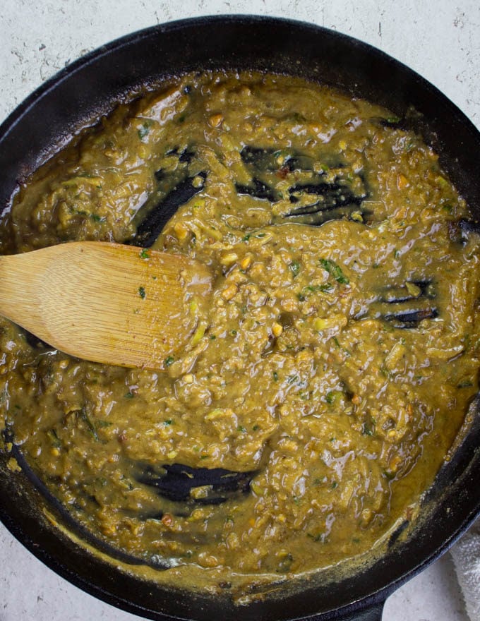 Apple peanut sauce being stirred in a black skillet 