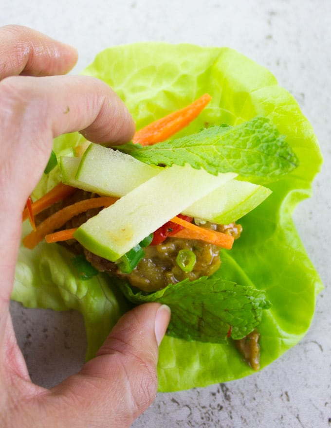 shredded apples being added to a chicken meatball lettuce wrap