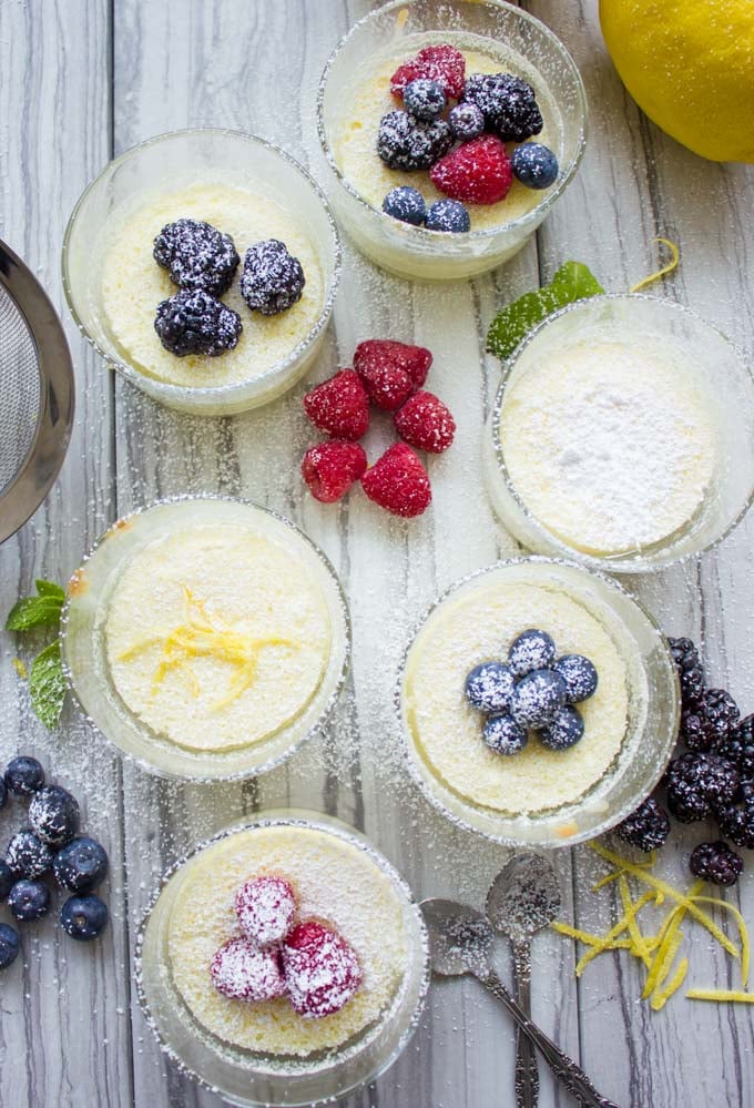 overhead shot of Easy Mini Lemon Pudding Cakes topped with fresh berries and icing sugar