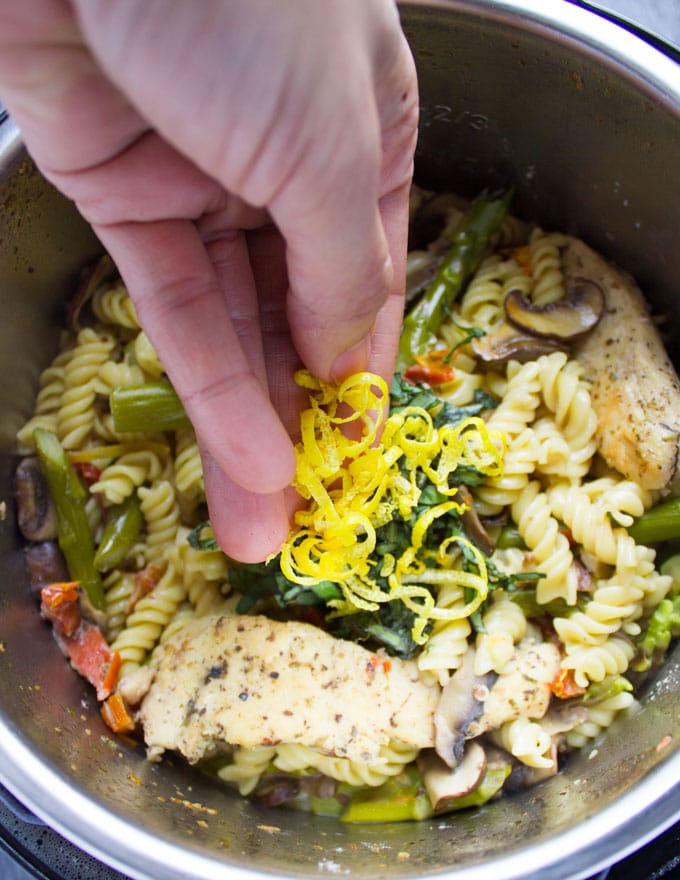 lemon zest being added to instant pot with chicken pasta