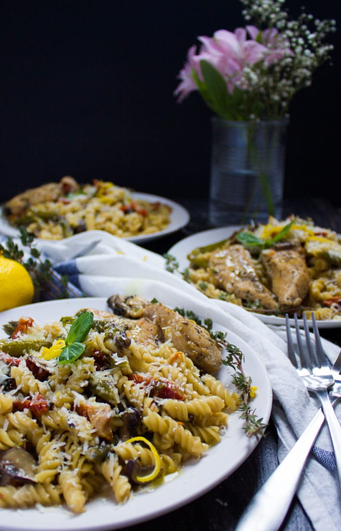 close-up side view of a white plate with creamy one-pot chicken pasta with grated parmesan on top