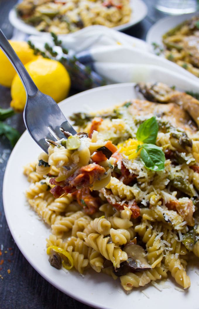 close-up of a plate of one-pot chicken pasta with veggies and shaved parmesan