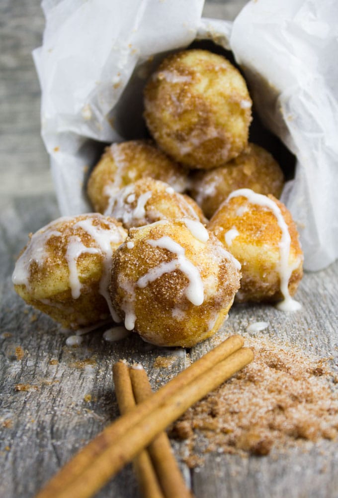 Baked Donut Holes with Cinnamon Sugar and Vanilla Glaze on a wooden table with some cinnamon sticks