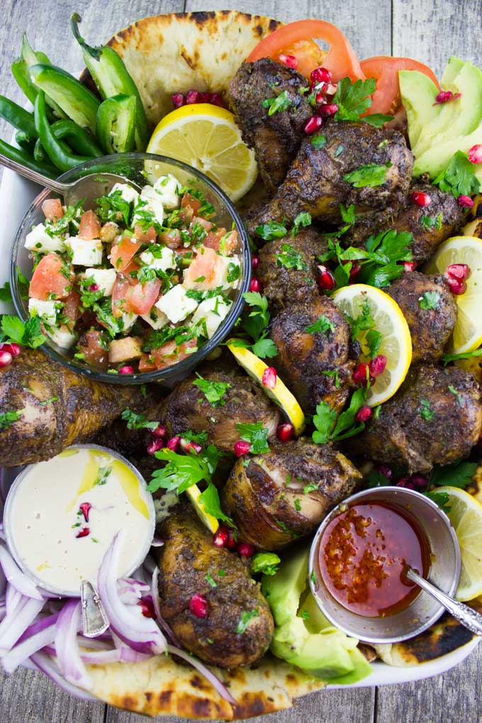 a small dish with tomato feta salad on a platter with chicken shawarma