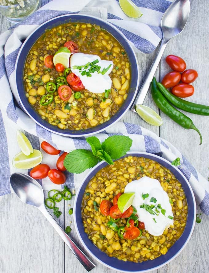 two blue bowls of Moroccan Lentil soup with lamb and turmeric topped with a dollop of yoghurt