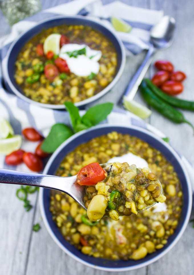 a spoon with Moroccan lentil soup with lamb and turmeric being balanced over a soup bowl