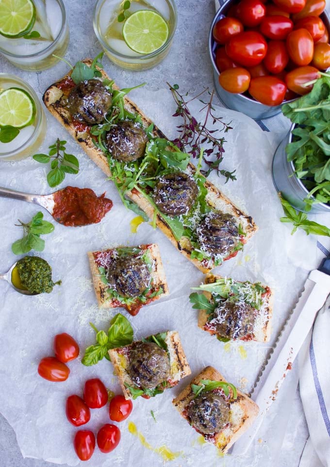 overhead shot of Grilled American Lamb Meatball Subs with marinara sauce and basil on parchment paper