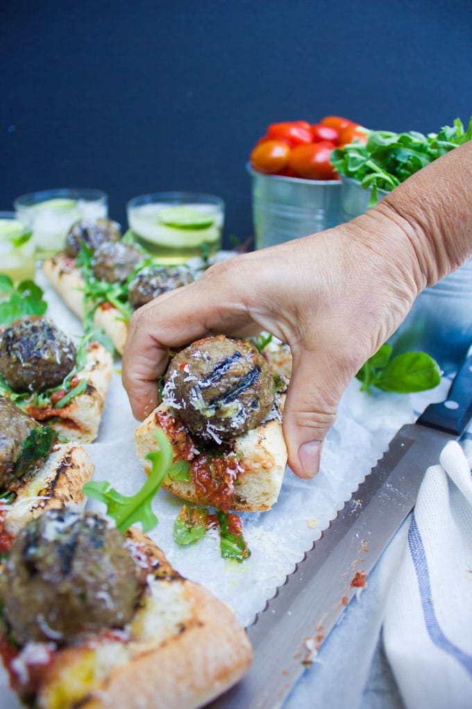 a hand reaching for a piece of Grilled American Lamb Meatball Sub