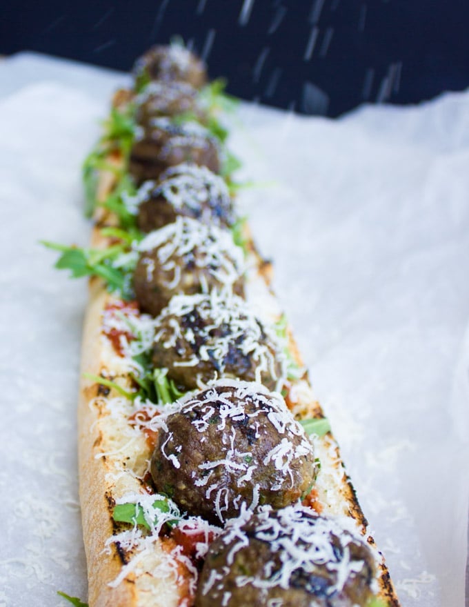 parmesan being sprinkled on an open American Lamb Meatball Sub