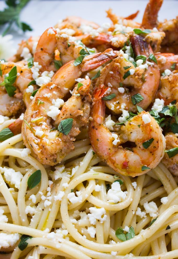 close-up of pasta topped with seared spiced shrimp and crumbled feta cheese