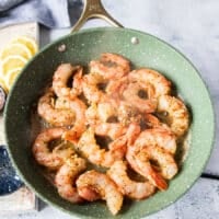 The shrimp is added in a single layer to a skillet at high heat for cooking