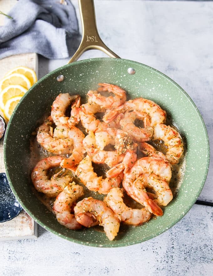 The shrimp is added in a single layer to a skillet at high heat for cooking 