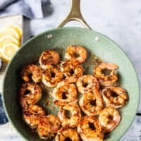 Pink and golden perfectly coked shrimp in a single layer in the skillet