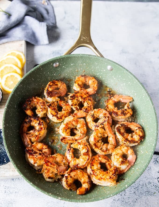 Pink and golden perfectly coked shrimp in a single layer in the skillet 