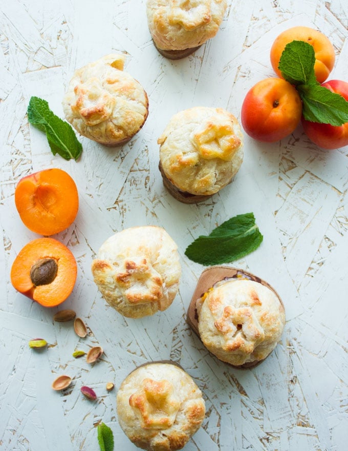 overhead shot of individual Whole Apricot Pies and peach pies with fresh apricots on the side