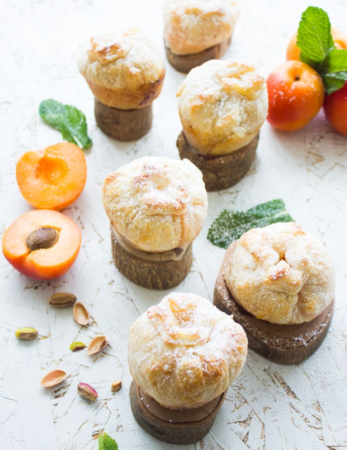 overhead shot of whole apricot pies and whole peach pies on small round pieces of wood