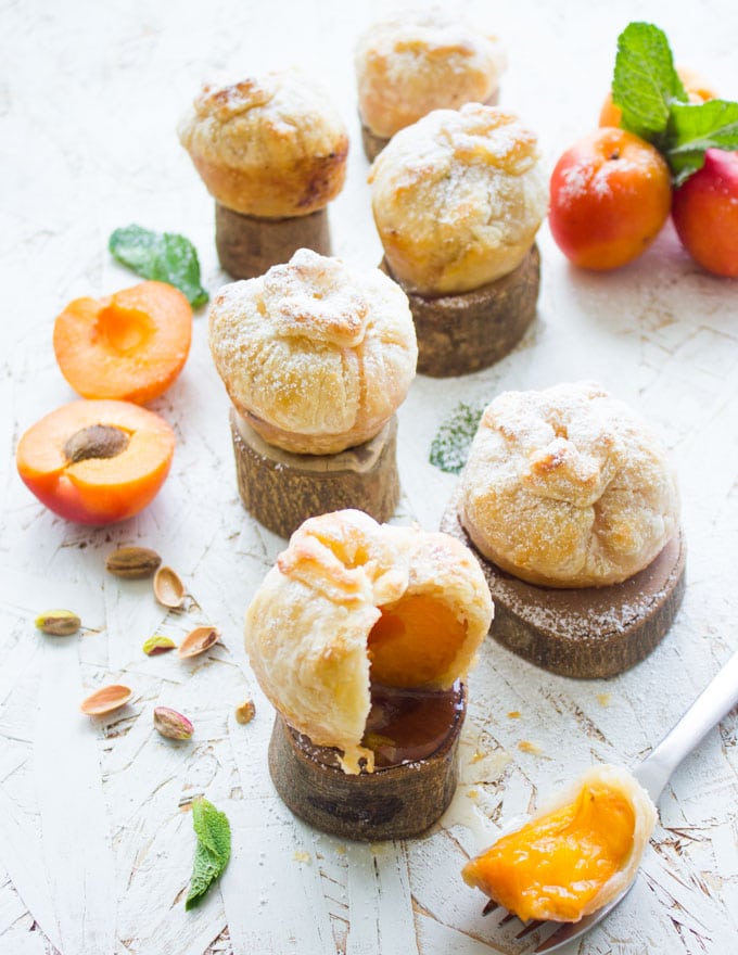 sugar-dusted individual Whole peach and Apricot pies arranged on small blocks of wood