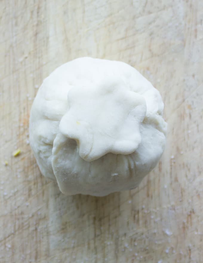 a pie pastry flower being pressed on top of a pastry wrapped apricot to seal