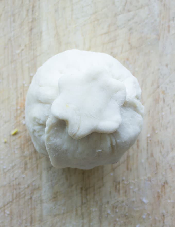 a pie pastry flower being pressed on top of a pastry wrapped apricot to seal