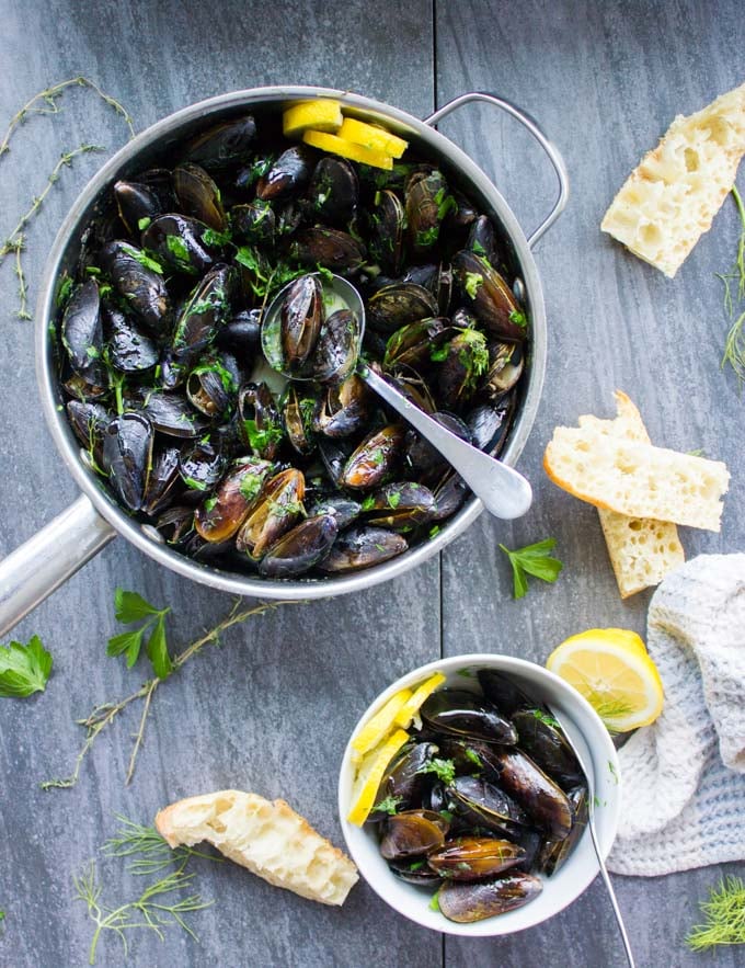 Top view of a full pot of mussels cooked in lemon sauce.